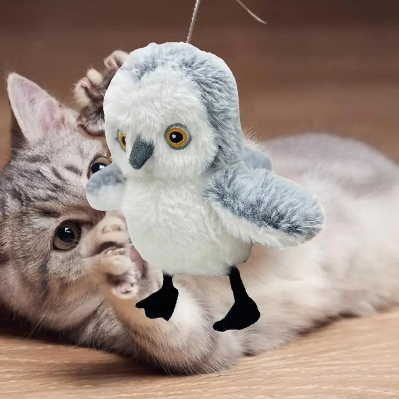 Un gato jugando con el búho de peluche