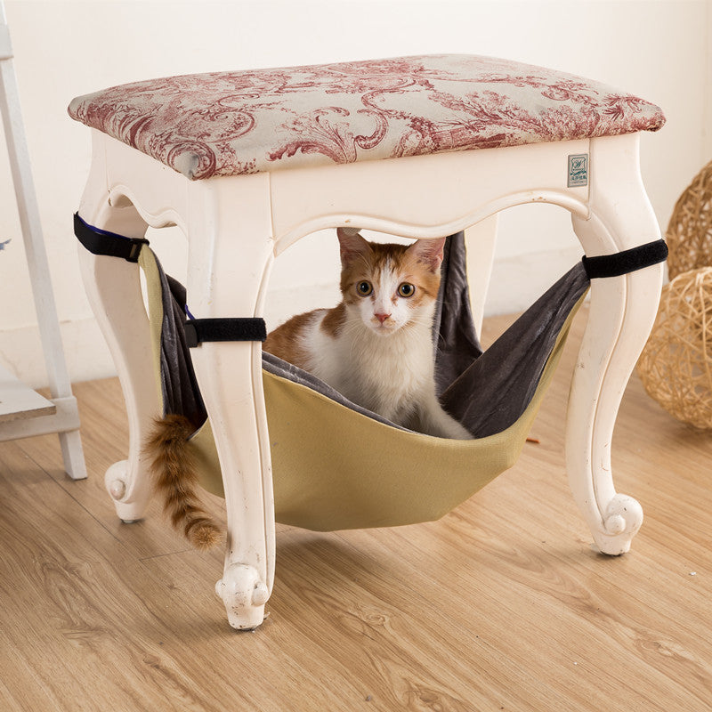 Gato en la hamaca crema bajo un taburete